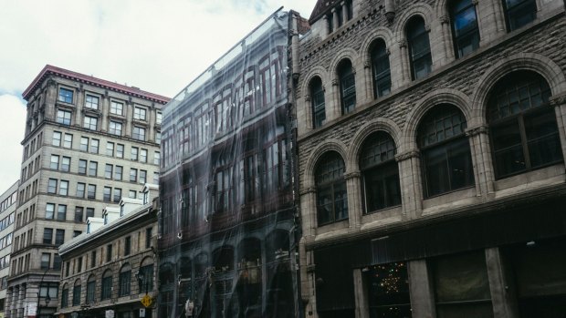 A heritage building being restored in Montreal whilst hidden by a canvas depicting the building underneath.