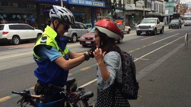 A young woman is pulled over in Sydney Road and shown how to wear her helmet correctly in a police blitz.