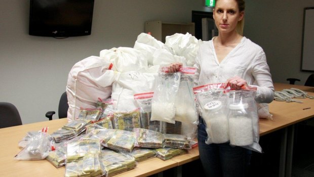 A police officer with the cash and drug haul. 