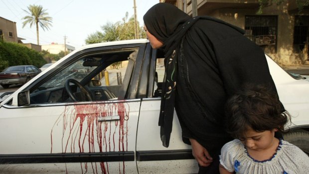 An Iraqi woman peers inside a blood stained car where two women were shot dead by the Blackwater guards. 