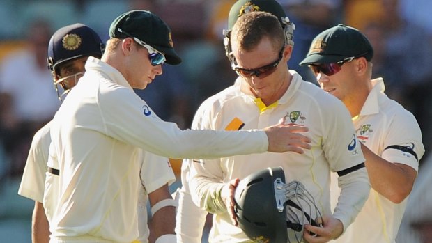 Chris Rogers inspects his helmet after he was hit in the head at the Gabba. 