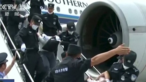 Uighurs deported from Thailand are seen brought off an airplane by police at an unidentified location in China.