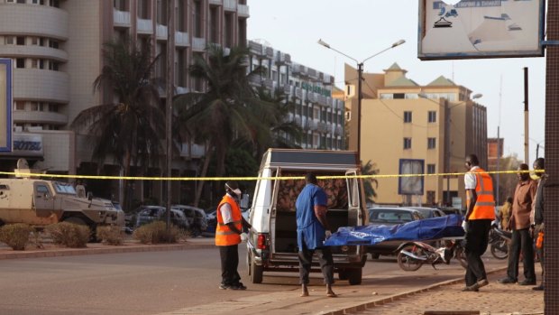 A body is carried near the Splendid Hotel, left, where militants attacked in Ouagadougou, Burkina Faso.