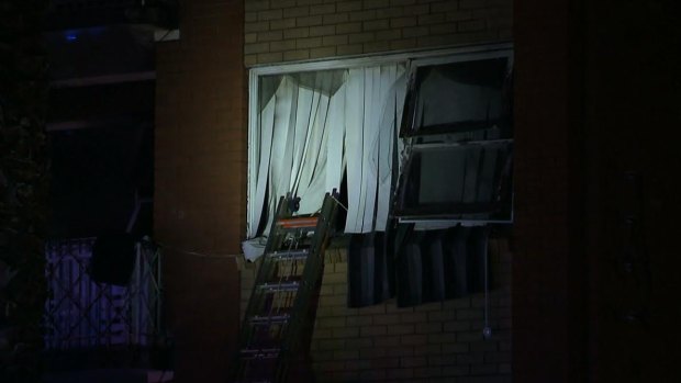 A woman, 27, was rescued from the windowsill of her burning apartment after dropping her two children to safety.