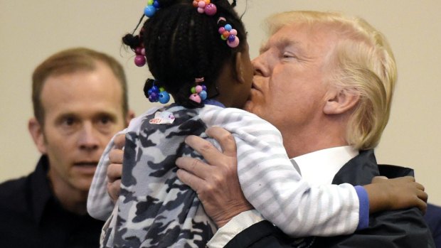 President Donald Trump greets a young survivor of the storms with a kiss on the cheek.