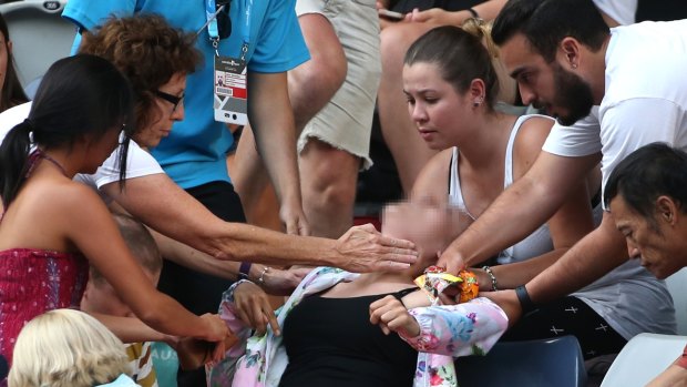 A tennis fan was helped by fellow spectators after she collapsed during Bernard Tomic's match with Denis Istomin.