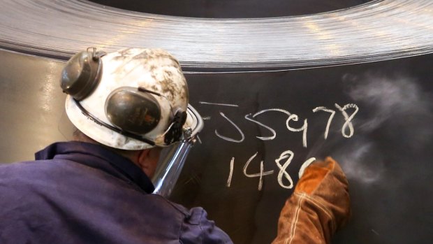 An employee marks a roll of coiled steel inside