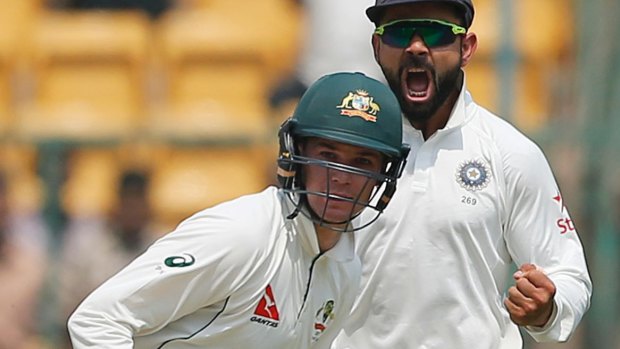 Virat Kohli, right, celebrates the dismissal of Australia's Peter Handscomb.