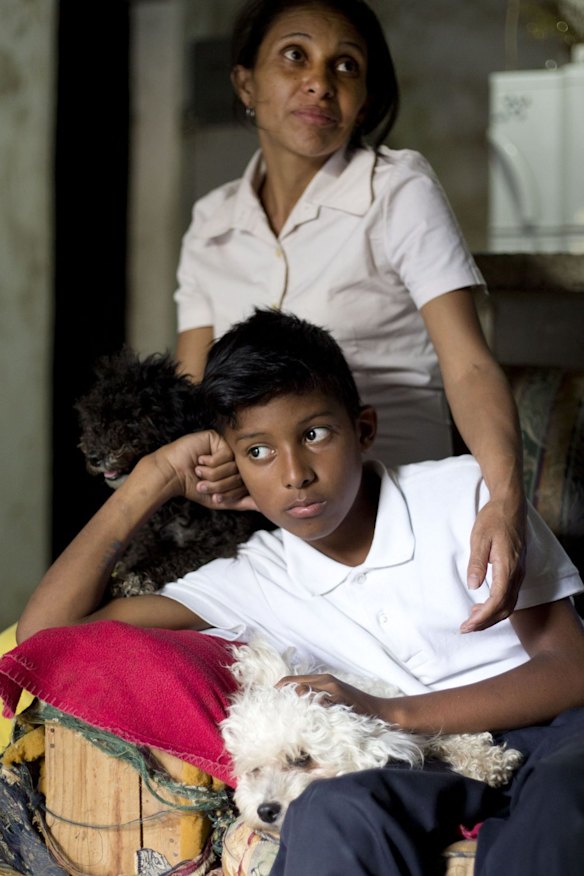 Roberto Bernal's widow Argelia Gamboa and her 11-year-old son Royber Fuentes sit in their home in a hillside slum in Caracas, Venezuela. 