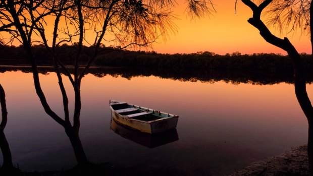 A boat on the Noosa River during sunset; Mt Coonowrin.