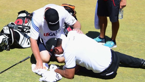 Jason Day of Australia is tended to by caddie Colin Swatton after collapsing.