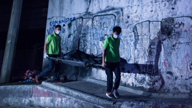 Mortuary workers carry the body of a summary execution victim on a stretcher in Manila. 