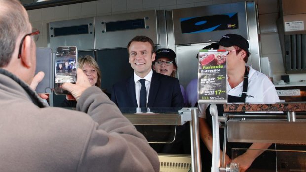 French centrist candidate Emmanuel Macron poses with employees at a fast-food restaurant.