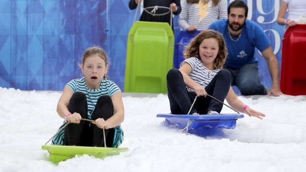 Sienna Crocket, 10, and Lottie Nehill, 10, try out the toboggan at the Winter Festival being held in King George Square.