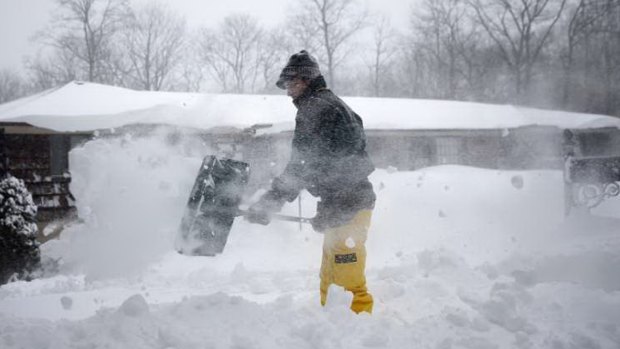 A man shovels snow from his driveway in the Long Island suburb of Dix Hills, New York. 