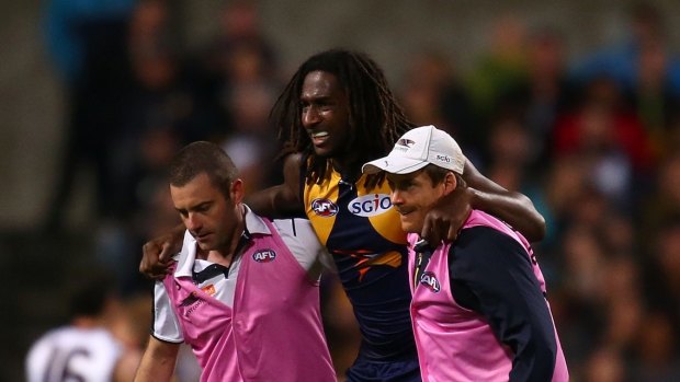 Nic Naitanui is helped from the ground after injuring his knee.