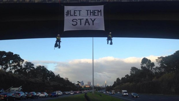 Two women hang with a sign from a bridge in Melbourne to protest against the forced deportation of refugees to Nauru, including babies and children.