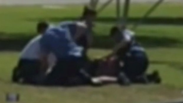 The officer appears to repeatedly punch the man on the ground.