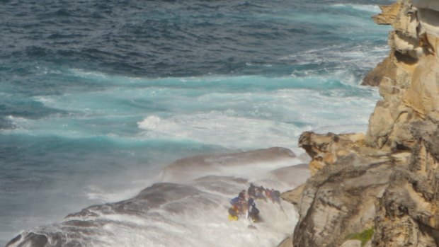 A wave sweeps over rescuers on the rock shelf at North Curl Curl.
