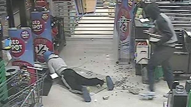 A screen grab from a CCTV video showing one of the men tripping and falling as he tries to flee with cash.