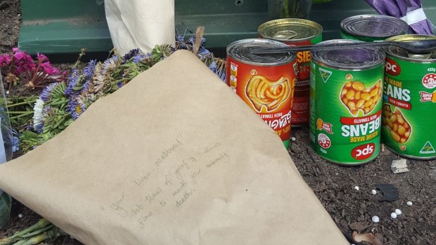 Cans of food and flowers left at the scene of the factory fire which claimed three lives.