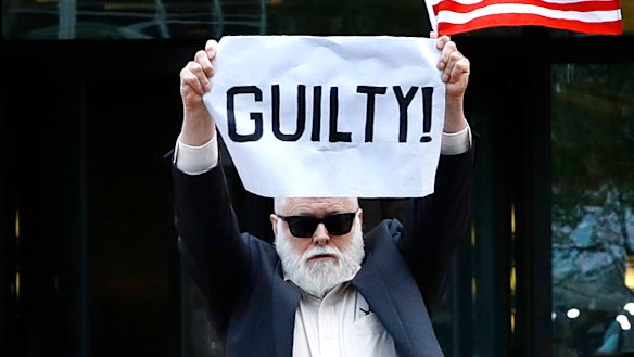 Protester Bill Christeson holds up a sign as the first count of guilty comes in.