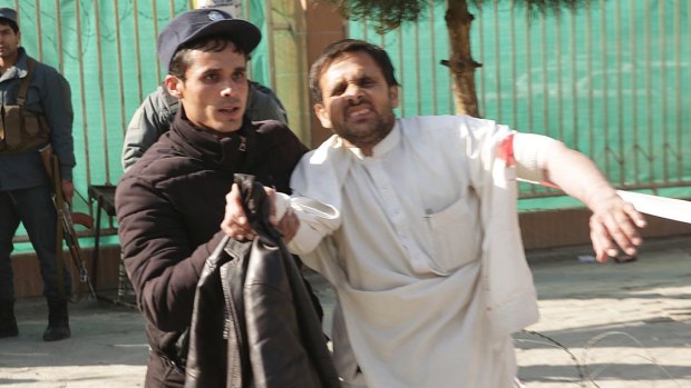 A wounded man is assisted after the attack in Kabul on Saturday.