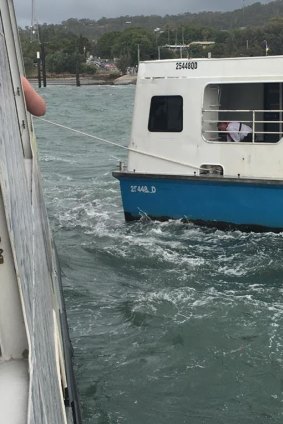 A small water taxi and a cable are used to try to tug the large car barge off the sand bar.