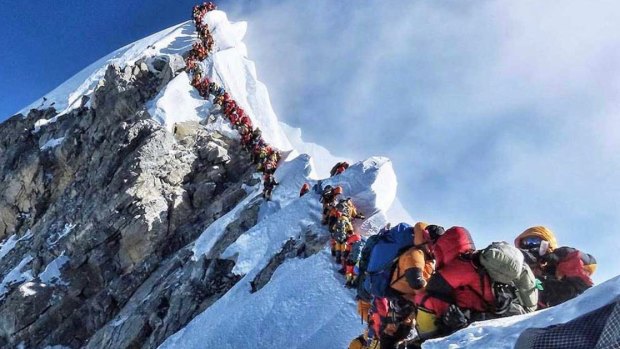 Climbers line up to stand at the summit of Mount Everest. 