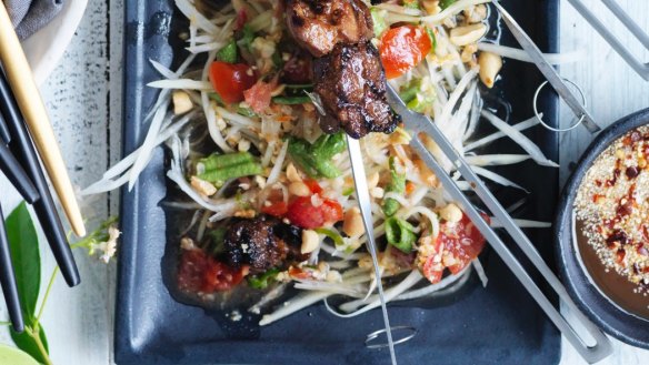 Green papaya salad used as a bed for grilled pork skewers.