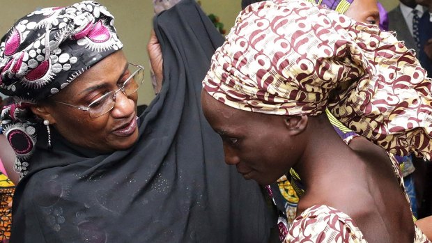 One of the released girls (right) is met by a Nigerian government official in Abuja.