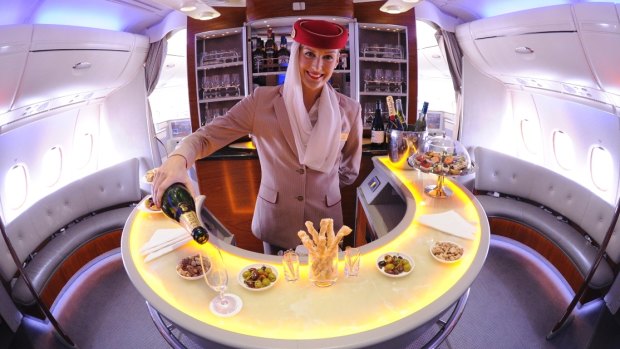 Cabin crew serve champagne in the onboard lounge on an Emirates A380.