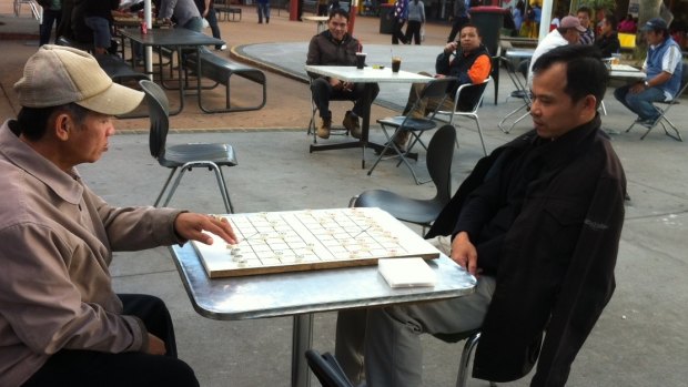 Men playing checkers at Inala Plaza.