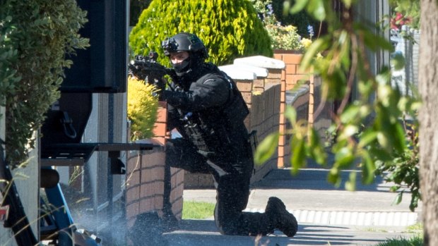 An armed officer takes up position outside the St Albans house.