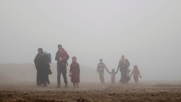 Displaced people walk through heavy fog during fighting between Iraqi security forces and Islamic State militants in west Mosul.