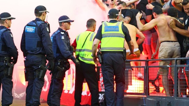 Smoke alarm: Wanderers fans let off flares as police officers look on in Melbourne two weekends ago.