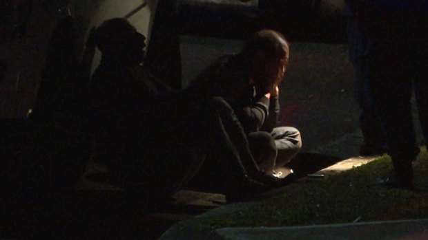 Two men sit in the gutter after a girl was shot dead in Lalor Park.