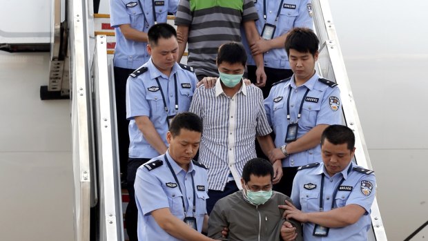 Six accused fugitives are taken back to China under escort from Indonesia in June 2015.