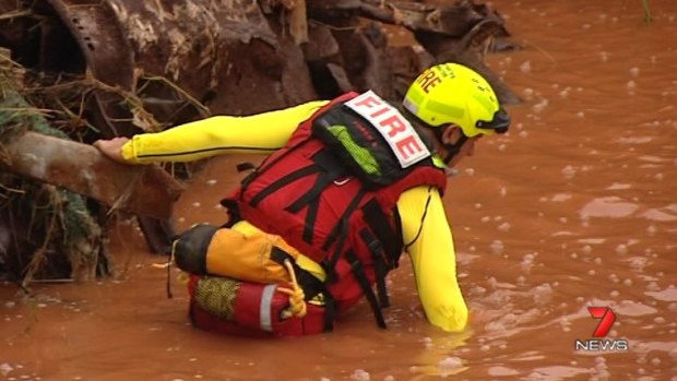 Emergency workers search for a man who went missing in flood waters at Tolga, west of Cairns.
