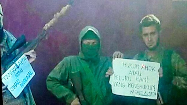 Members of the Syria-based jihadist group Jabhat Fatah al-Sham hold a sign that reads "Punish Ahok or our bullets will".