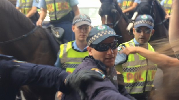 Officers form a line as students point their fingers and chant 'shame'.