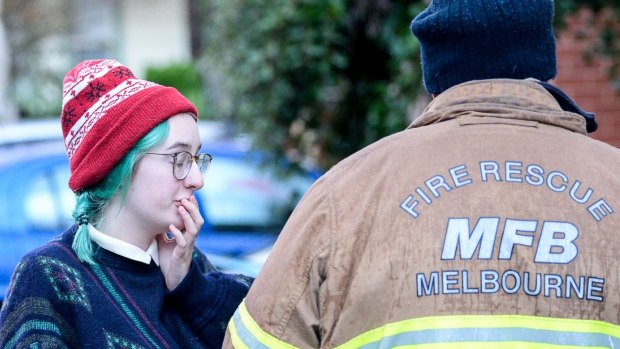 Amelia Reeves who rents one of the flats speaking with a firefighter where her home was one of the townhouses destroyed in Hope Street, Brunswick.