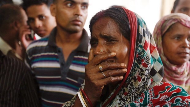 A relative of a fire victim cries as victims' bodies are carried into a makeshift morgue.