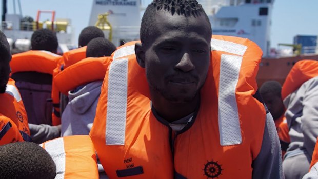 Migrants aboard a dinghy in the Mediterranean Sea wait to be rescued.