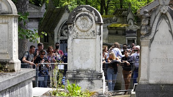 Fans gather at the tomb of rock singer Jim Morrison at the Pere-Lachaise cemetery in Paris on Saturday.