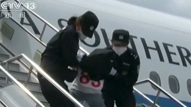 One of the Uighurs is taken off a plane in China.