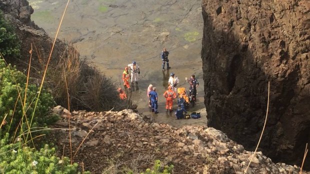 Emergency services move the 17-year-old who fell from a cliff face at Loves Bay onto a stretcher.
