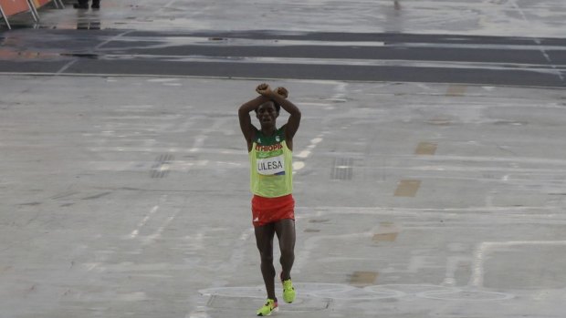 Moment of protest: Ethiopia's Feyisa Lilesa crosses his arms as he crosses the finish line.
