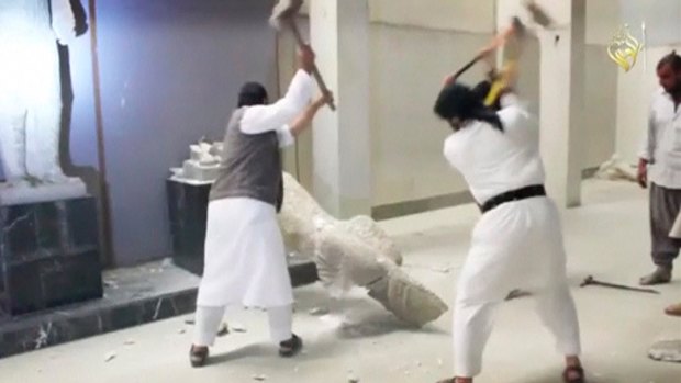Jihadists use sledgehammers on a toppled statue in a museum at a location thought to be Mosul. 