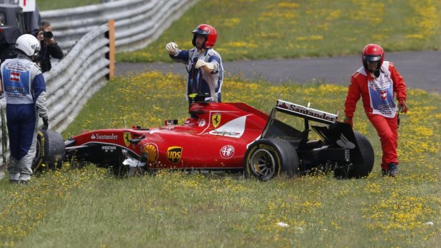 Marshalls retrieve the car of Kimi Raikkonen of Finland and Ferrari after he crashed.